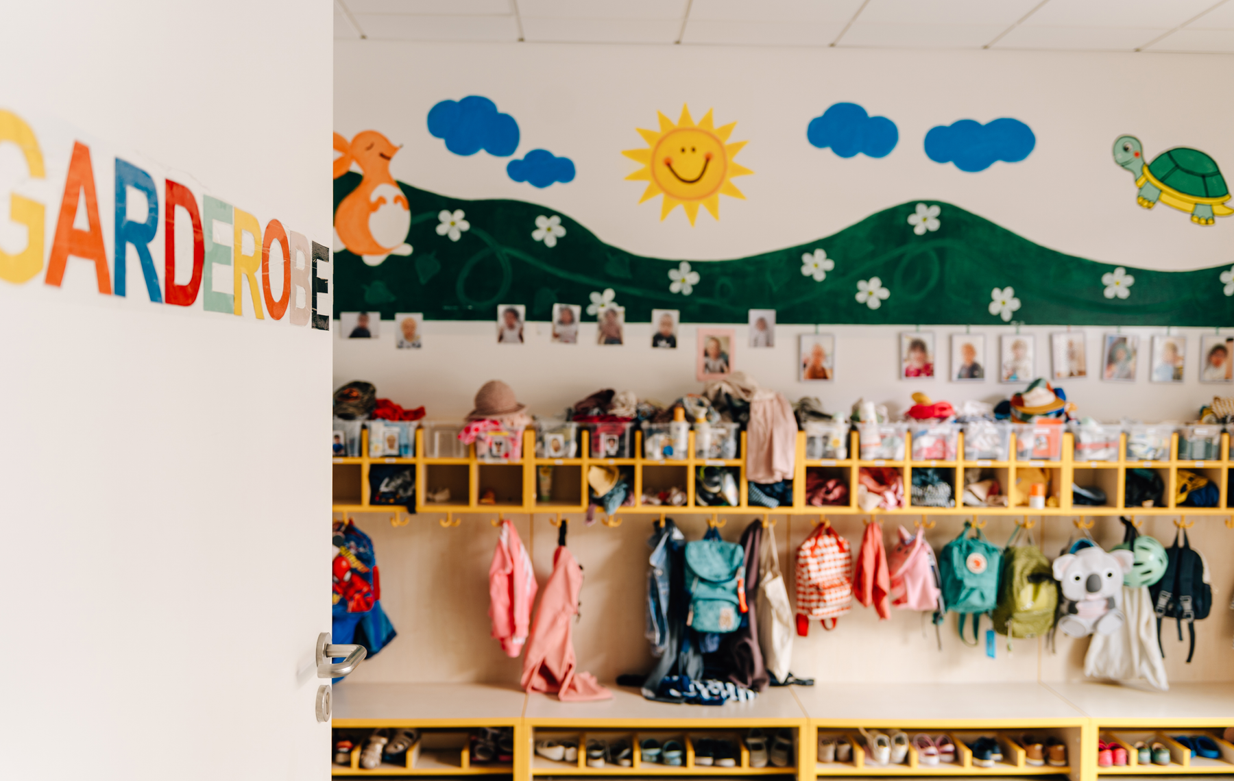 Garderobe mit Jacken, Schuhen, und Bilder der Kinder